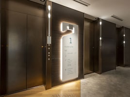 Interior moderno de elevador com indicador de andares mostrando os níveis 16 e 3, e uma receção do lobby.