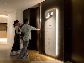 Elevador de hotel com guia de andares indicando os níveis de 1 a 3, incluindo quartos de hóspedes, lobby, recepção, armários, máquina de vendas automática, restaurante, lavanderia, máquina de gelo e sala de reuniões.