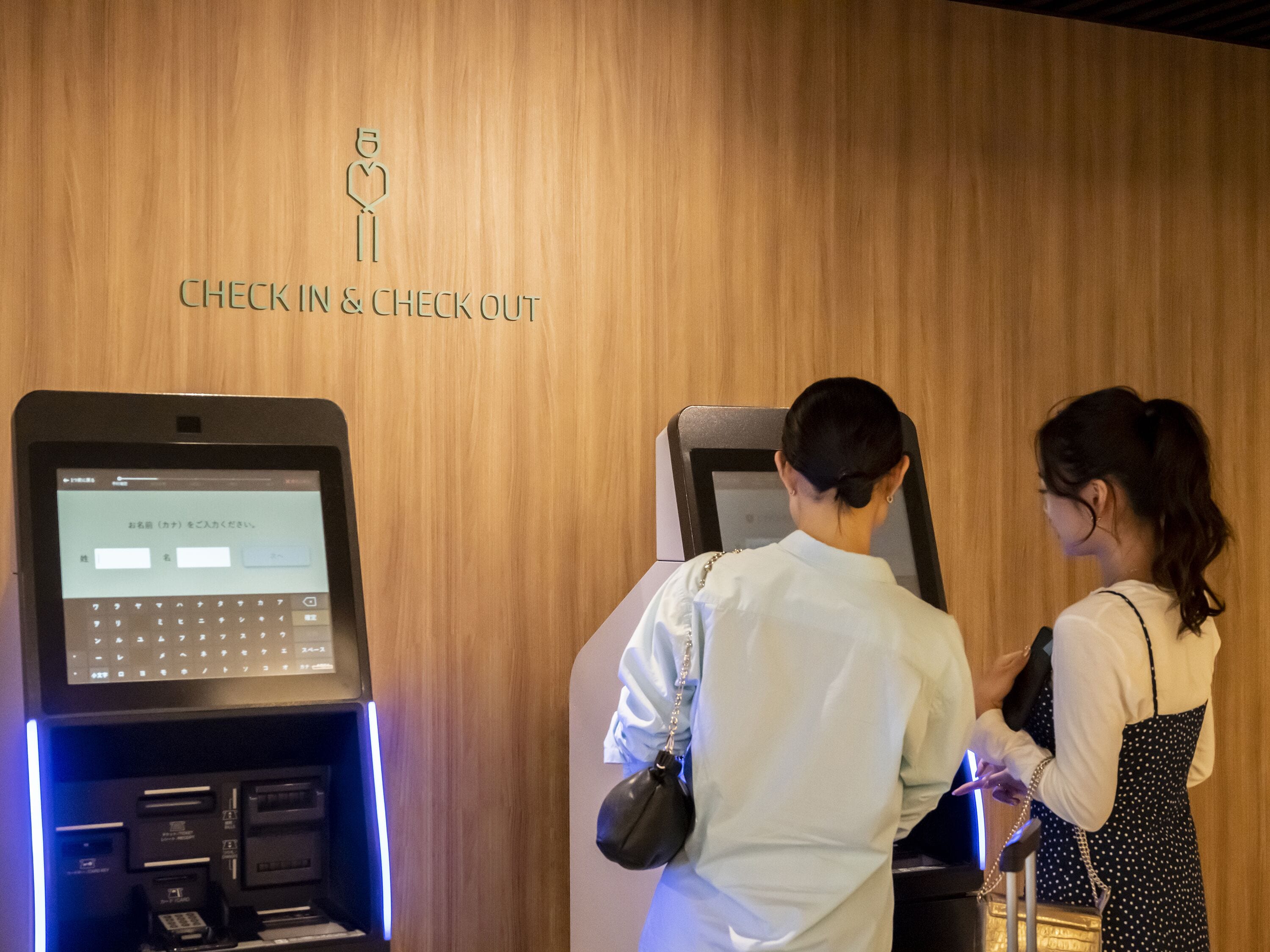 A check-in and check-out kiosk with a wooden wall background.
