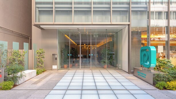 A modern building entrance with a glass facade, a tiled pathway, and a teal sculpture. - Prince Smart Inn Osaka Yodoyabashi (Osaka)