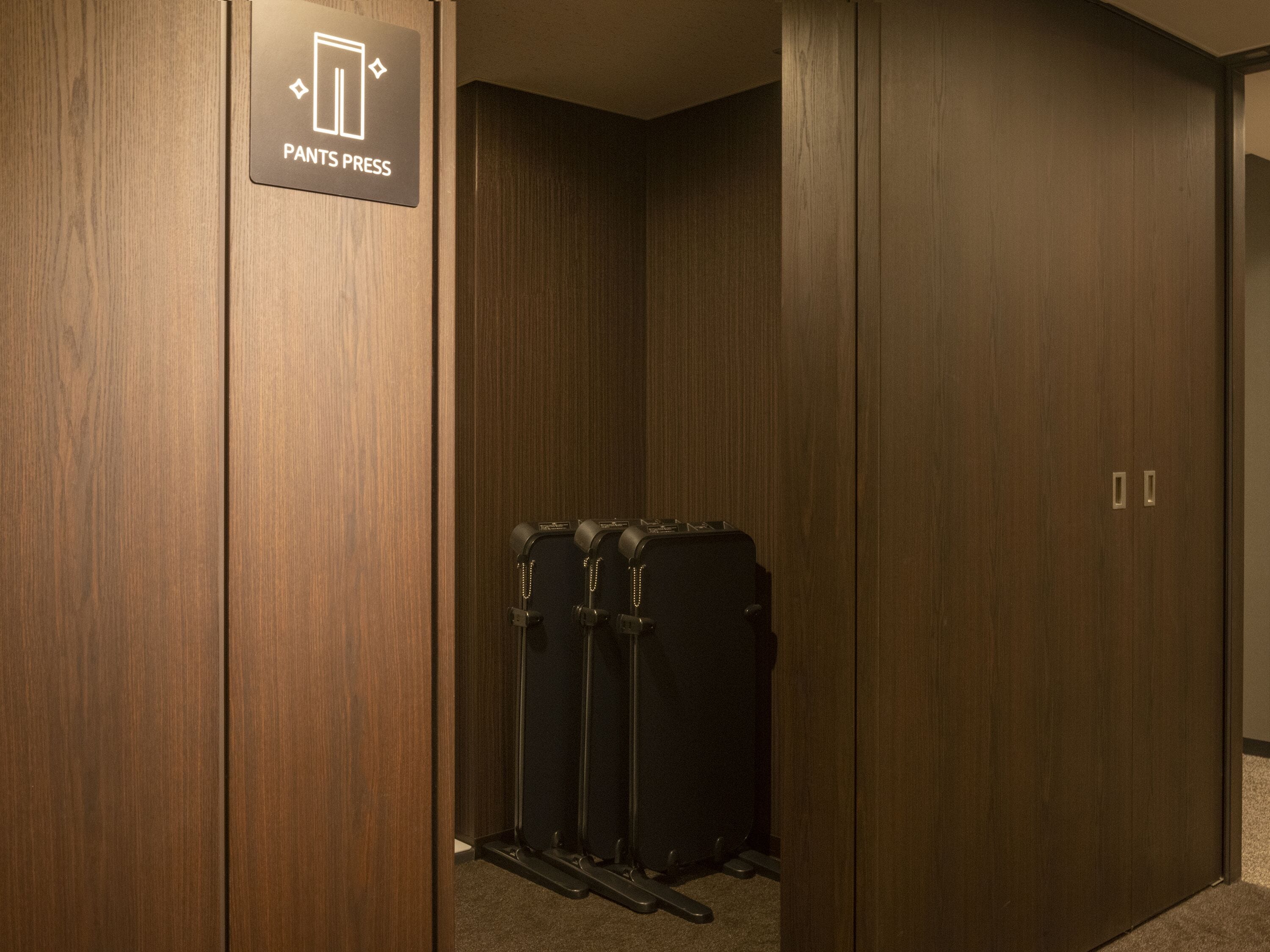 A wooden-paneled room with a sign indicating a 'Pants Press' service.