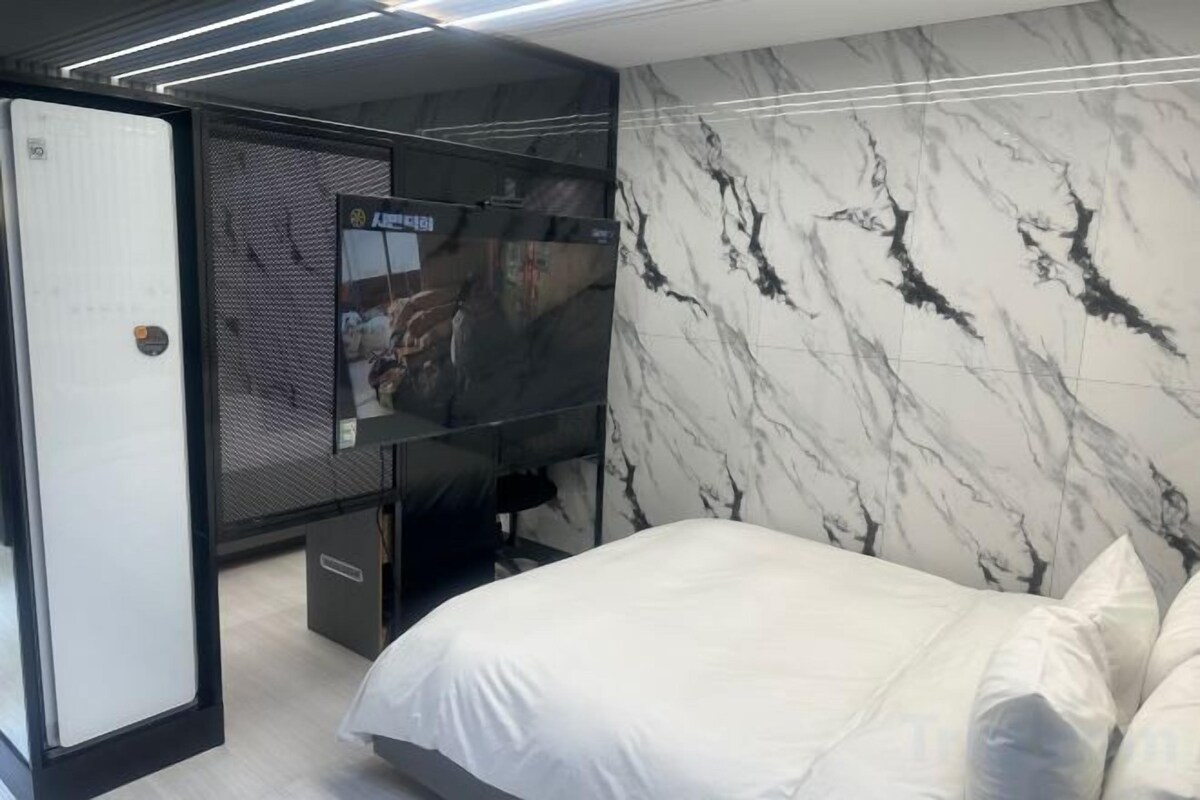 Une chambre moderne avec un lit, une télévision et un mur en marbre.