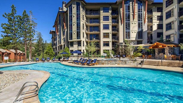 A hotel with a swimming pool, lounge chairs, and a stone patio. - Pet-Friendly in Luxury Hotel. Across The Village, EV Charging Station On-site (Mammoth Lakes)
