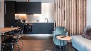 Une cuisine moderne avec des meubles de couleur sombre, une table à manger en bois et un canapé bleu clair.