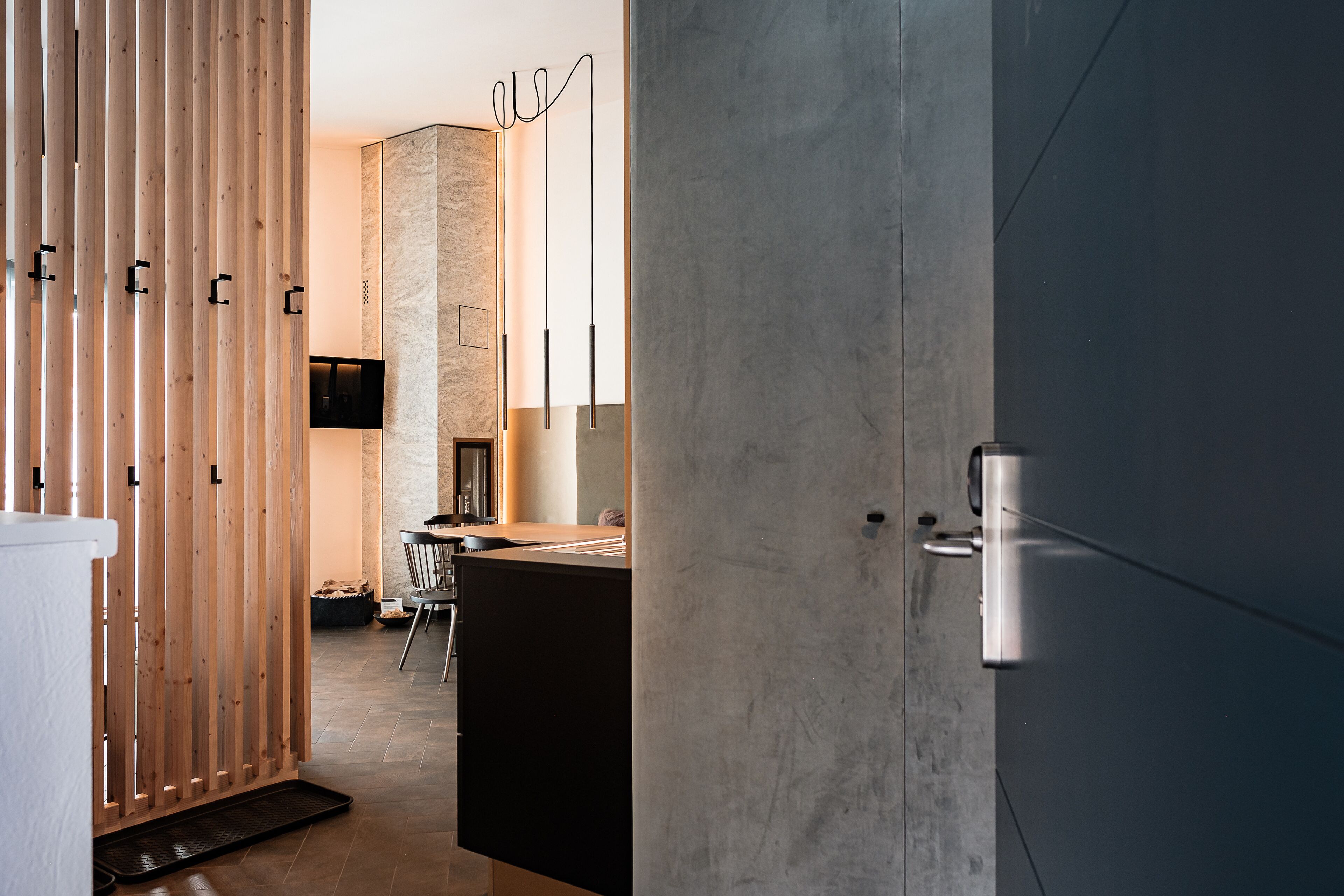Un interior moderno con un separador de madera, un pilar de piedra y una puerta de estilo minimalista.