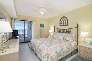 Una camera da letto con un letto, comodini, una scrivania, una ventola a soffitto e vista sull'esterno.
