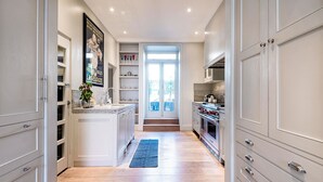 A kitchen with white cabinetry, a blue rug, and a view through a glass door. - Notting Hill Townhouse - by Out of Office Lifestyle (London)