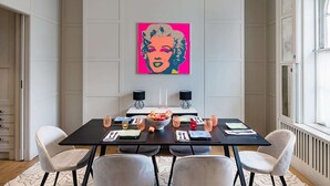 A dining area with a table set for four, two wall-mounted speakers, and a large pop art painting on the wall. - Notting Hill Townhouse - by Out of Office Lifestyle (London)