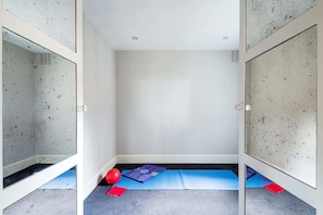 Um quarto pequeno e vazio com um tapete azul e uma bola vermelha no chão.