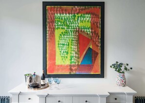 A framed abstract painting on a white wall, a bottle of wine, and two glasses on a white table. - Notting Hill Townhouse - by Out of Office Lifestyle (London)