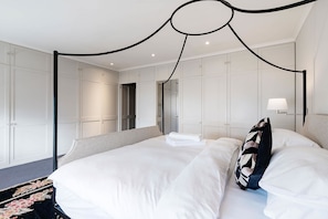 A modern hotel room with a four-poster bed, a flat-screen TV, and a large mirror. - Notting Hill Townhouse - by Out of Office Lifestyle (London)