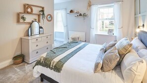 Une chambre à coucher avec un lit, une commode et une fenêtre avec des rideaux.