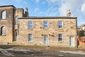 A stone building with multiple windows and a door, likely a residential property.