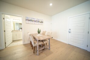 A dining area with a wooden table and chairs, a potted plant, and a wall-mounted poster. - Modern Keystone Condo | Lake Fun + Hot Tubs (Keystone)