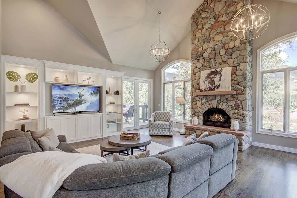 A living room with a stone fireplace, a large TV, and a cozy seating area.
