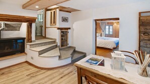 Een kamer met een open haard, een trap, een bed en een tafel met een tijdschrift.