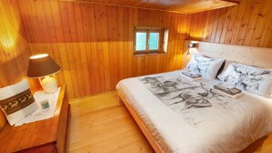 A wooden-paneled room with a bed, a nightstand, a lamp, and a window. - Apartment "Sweet Somma Mountain Lodge 2" with Mountain View, Private Terrace & Wi-Fi (Sommarovina)