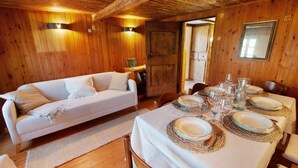A wooden interior with a sofa, dining table set with plates and glasses, and a map on a shelf. - Apartment "Sweet Somma Mountain Lodge 2" with Mountain View, Private Terrace & Wi-Fi (Sommarovina)