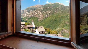 A window with a view of a mountainous landscape, a church, and a small village. - Apartment "Sweet Somma Mountain Lodge 2" with Mountain View, Private Terrace & Wi-Fi (Sommarovina)