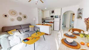 Un salon moderne comprenant un canapé, une table basse et un coin repas avec des chaises et une table.
