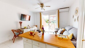 Un salon moderne avec une table à manger en bois, un canapé, un téléviseur fixé au mur et un appareil de climatisation.
