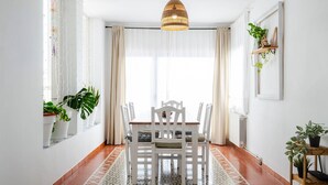 A dining area with a white table and chairs, a patterned floor, and a hanging light fixture. - Villa "El Riu del Cel" with Private Garden, Private Pool, and Wi-Fi (Lloret de Mar)