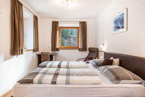 Une chambre d’hôtel comprenant un lit, un bureau, une chaise, une fenêtre avec des rideaux et un tableau accroché au mur.