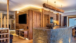 Un interior rústico con una isla de piedra, paredes de madera y un televisor de pantalla plana.