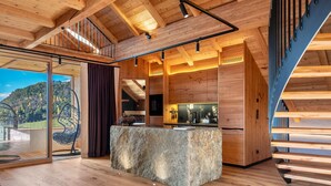 Un interior moderno con encimera de piedra, vigas de madera y vistas a un paisaje montañoso.