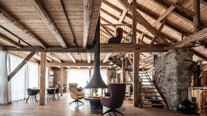 Una habitación amplia con un alto techo de madera, una chimenea y una escalera.