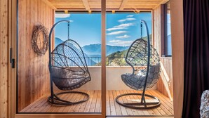 Interior de madera con dos sillones colgantes orientados hacia una vista panorámica de la montaña.