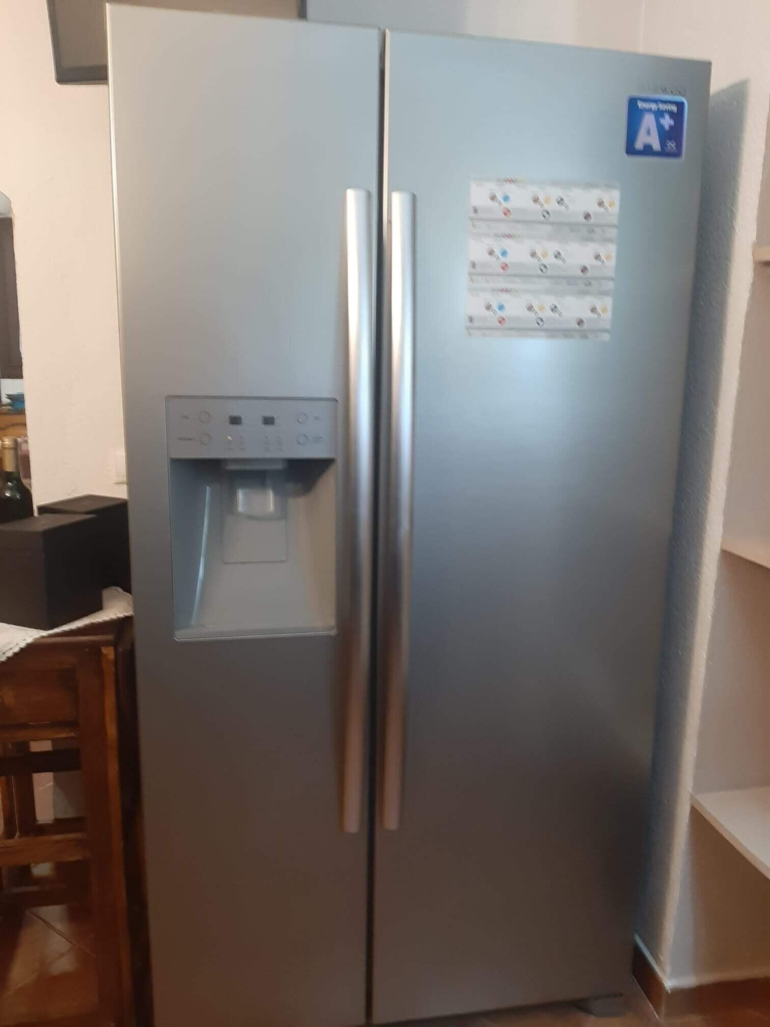 Et stålskab med kølesektion og vanddispenser samt en blå energimærkat.