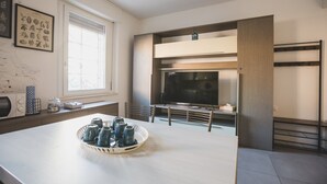 Eine moderne Küche mit einer großen Kochinsel, einem integrierten Fernseher und einem Fenster mit Jalousien.