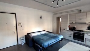Ein kleines Hotelzimmer mit Bett, Küchenzeile und Esstisch.
