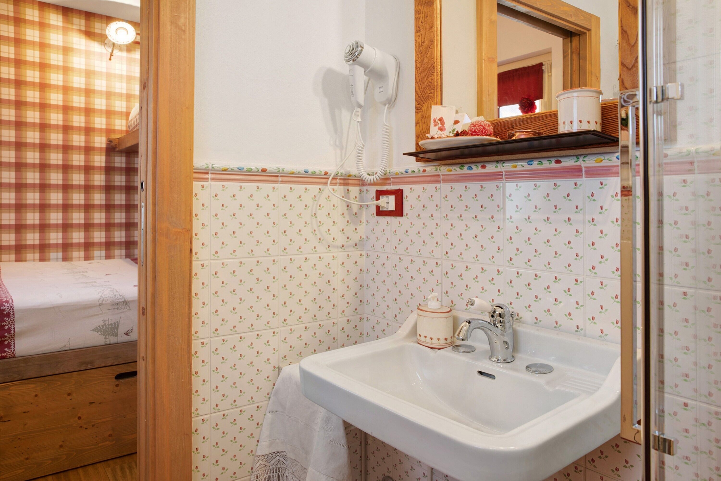 Ein Badezimmer mit Waschbecken, Fön, Spiegel und Dusche.
