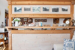 Un estante de madera con marcos de fotos, una jarra blanca y varios utensilios de cocina.