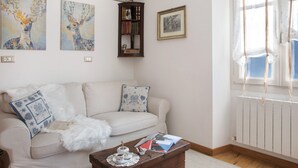 A living room with a sofa, a coffee table, a bookshelf, and artwork on the walls. - Holiday Apartment "Mantaula" with Mountain View, Shared Terrace & Wi-Fi (Teglio)