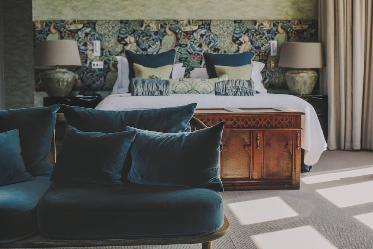 Un dormitorio con una cama, dos mesitas de noche, un baúl de madera y un sofá azul.