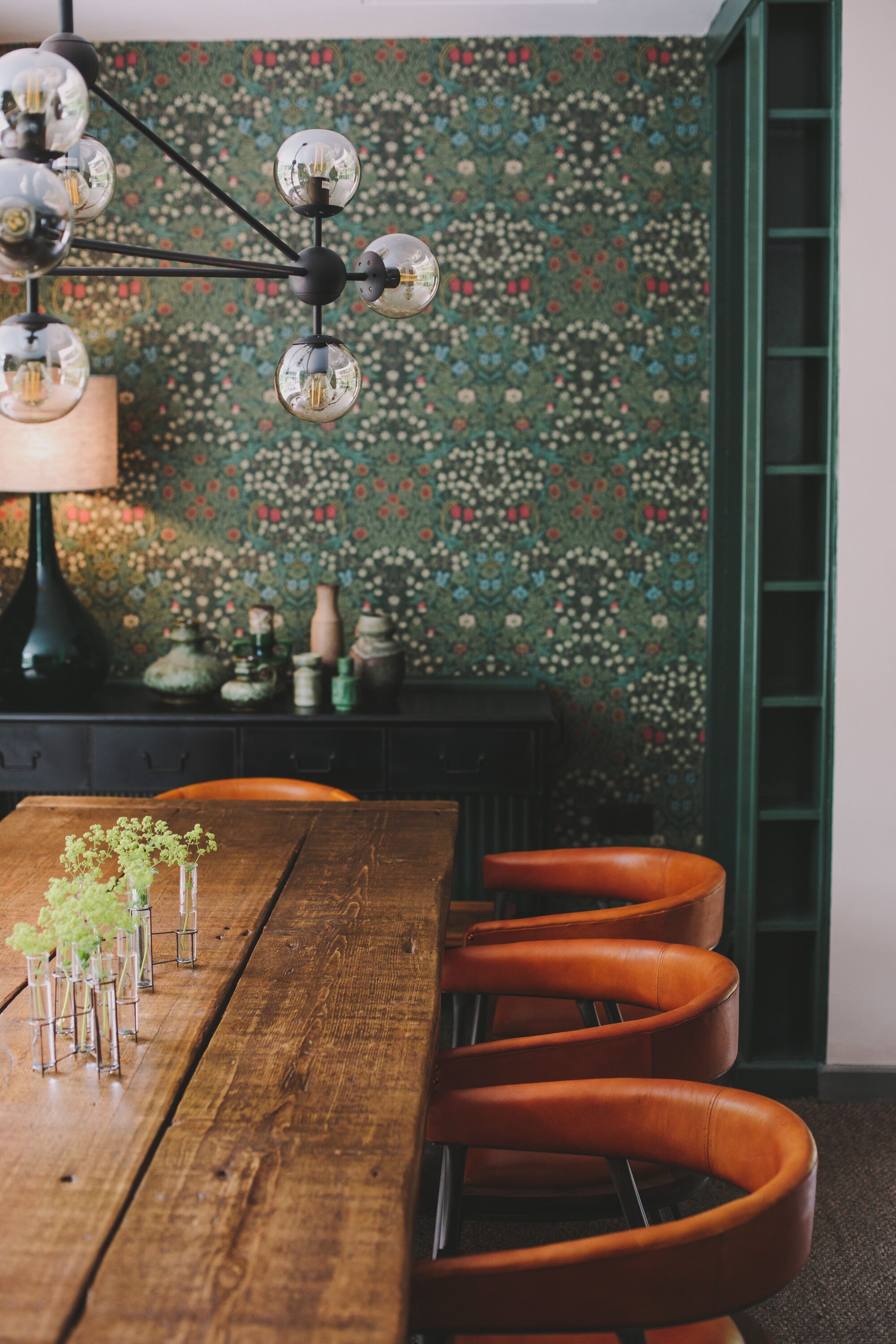 A wooden dining table with chairs, a patterned wall, and a hanging light fixture.