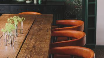 A wooden dining table with chairs, a patterned wall, and a hanging light fixture.