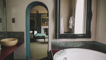A bathroom with a large mirror, a bathtub, and a stone basin.