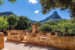 An ancient stone structure with steps and ruins, surrounded by trees and mountains under a clear sky. - Finca "Can Jaumi" with Sea Views, Pool and Wi-Fi (Artà)