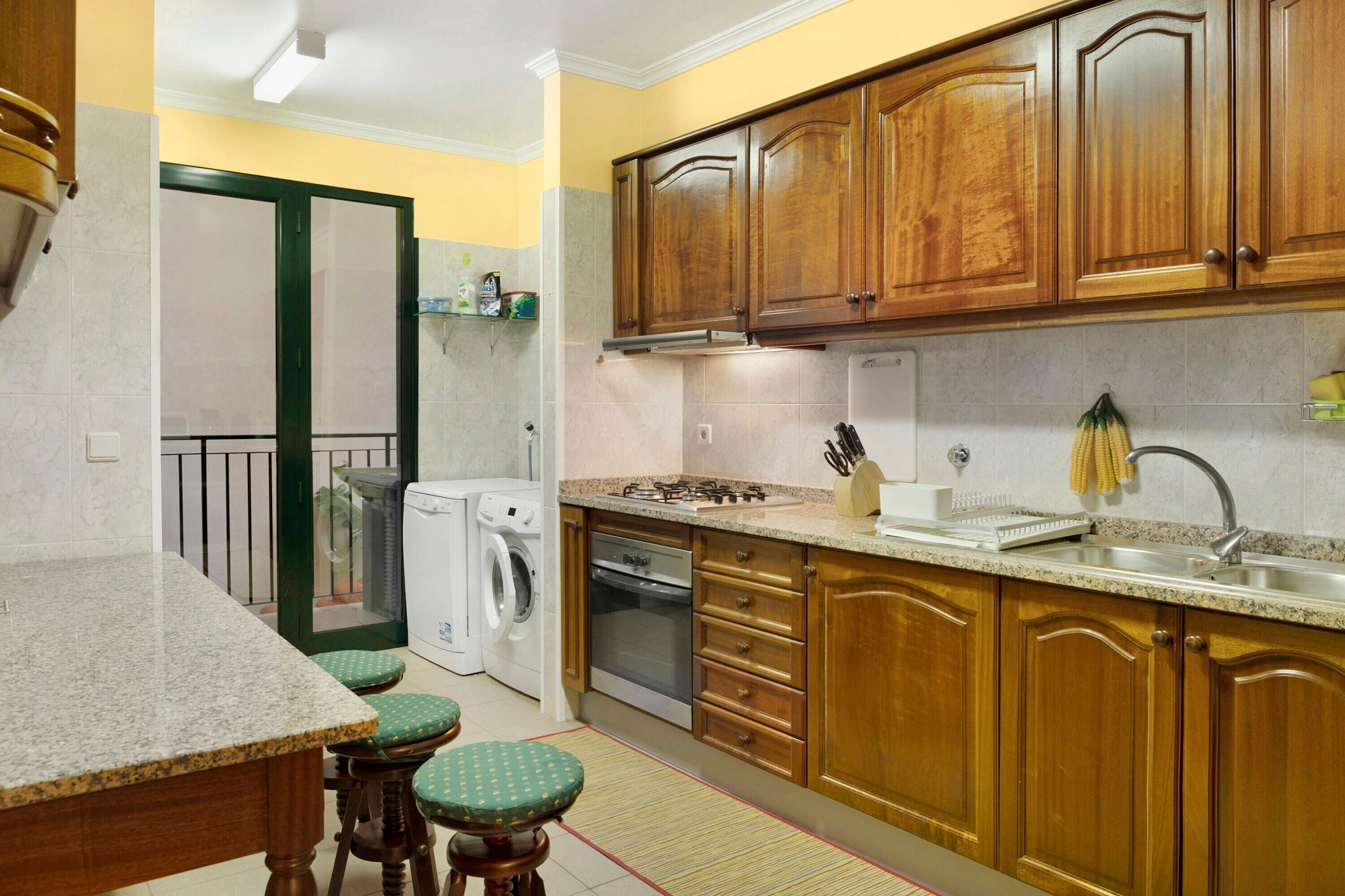 Una cocina con armarios de madera, lavadora, estufa y lavaplatos.