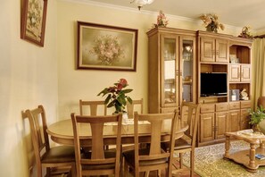 Une salle à manger avec une table et des chaises en bois, un tableau au mur et un buffet aux portes vitrées.
