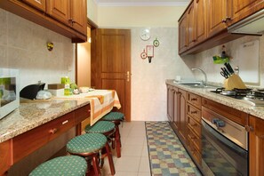 Une cuisine avec des meubles en bois, un plan de travail en granit, une cuisinière et des tabourets de bar.