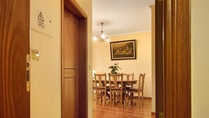 A wooden door with a lock, a wall-mounted electrical outlet, and a framed picture above a dining table with chairs. - Holiday Apartment "Palheiro Residence Familiar 1" with Sea View, Balconies & Wi-Fi (Funchal)