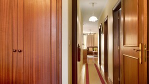 A wooden hallway with a carpet, a chandelier, and a door leading to a room. - Holiday Apartment "Palheiro Residence Familiar 1" with Sea View, Balconies & Wi-Fi (Funchal)