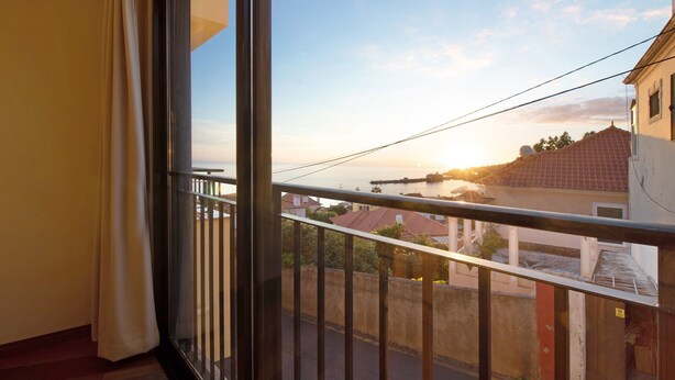 A balcony with a view of a sunset over a coastal town. - Holiday Apartment "Palheiro Residence Familiar 1" with Sea View, Balconies & Wi-Fi (Funchal)