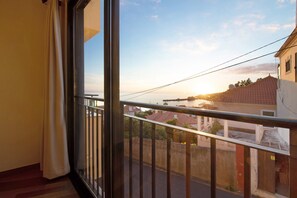 Un balcon offrant une vue sur le coucher de soleil au-dessus d’une ville côtière.