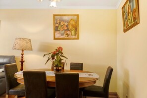 Un coin repas comprenant une table, des chaises, une lampe et un vase avec des fleurs.